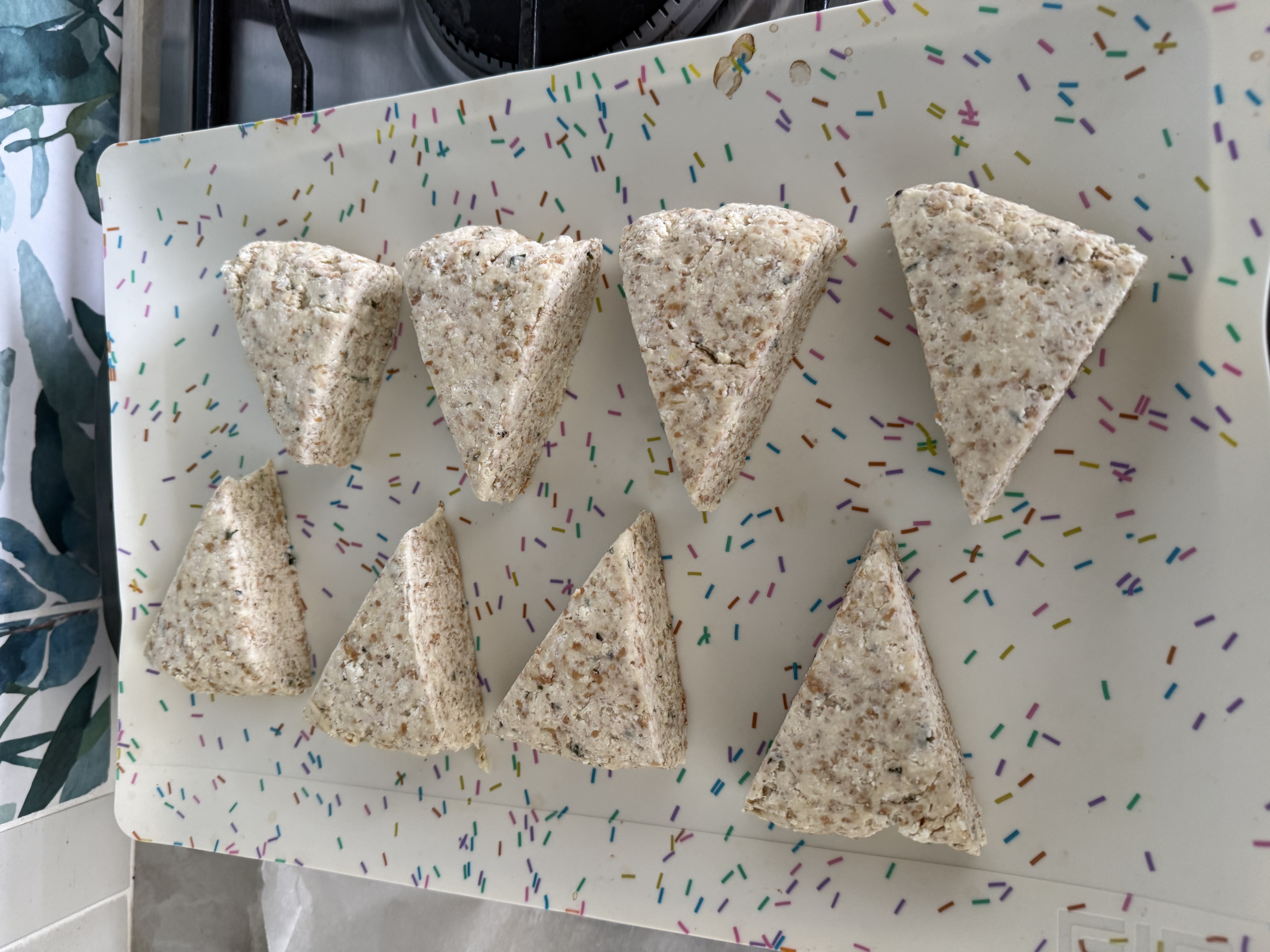 Eight chilled triangular herby ricotta scones shaped and ready to bake