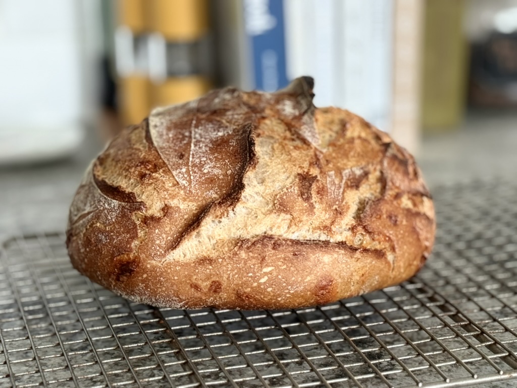 A croissant sourdough loaf on a cooling rack
