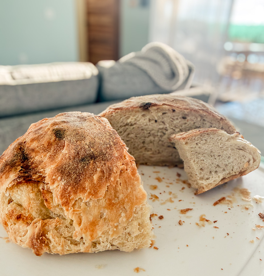 Two rustic homemade loaves, one sliced to show its crumb